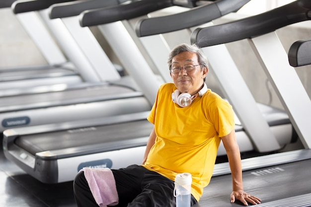 Retrato de sênior com óculos, fazendo exercícios no ginásio de fitness.