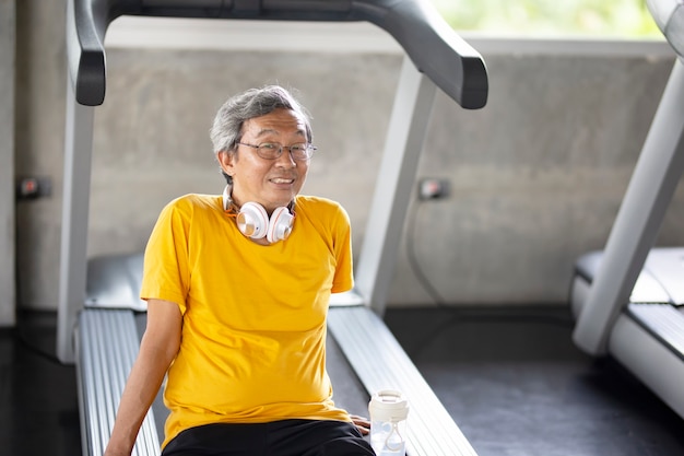 Retrato de sênior com óculos, fazendo exercícios no ginásio de fitness.