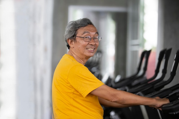 Retrato de sênior com óculos, fazendo exercícios no ginásio de fitness.