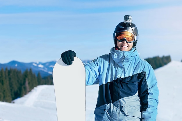 Retrato de snowboarder e snowboard em um fundo de montanhas