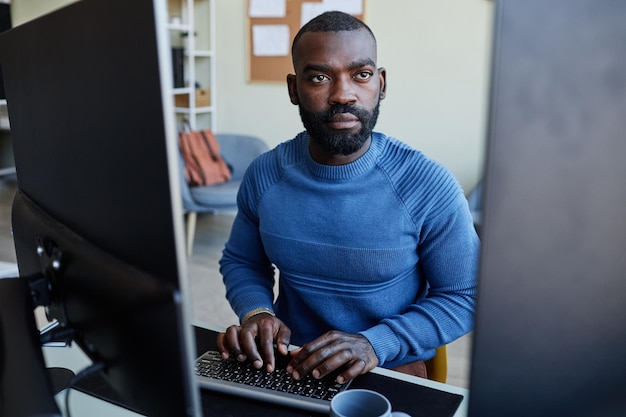 Retrato de software de programação de homem negro no local de trabalho com várias telas de computador