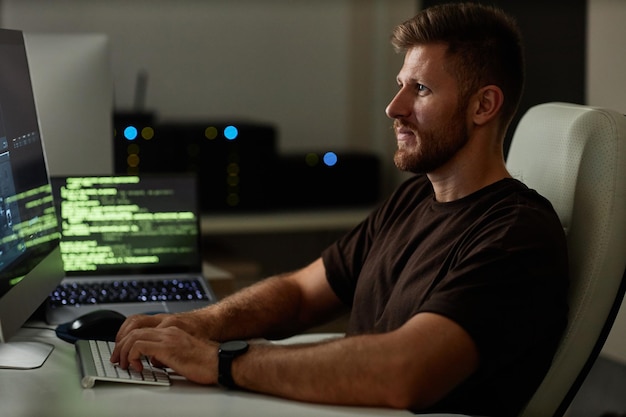 Foto retrato de software de programação de jovem no local de trabalho em luz noturna fraca