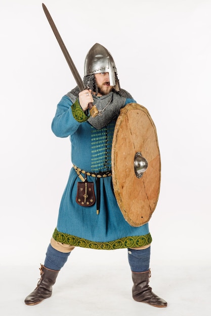 Retrato de soldado eslavo medieval em pé e pronto para uma luta com imagem de armadura de capacete de espada no conceito histórico de fundo de estúdio branco