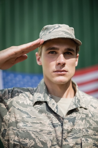 Retrato de soldado militar dando continência em campo de treinamento