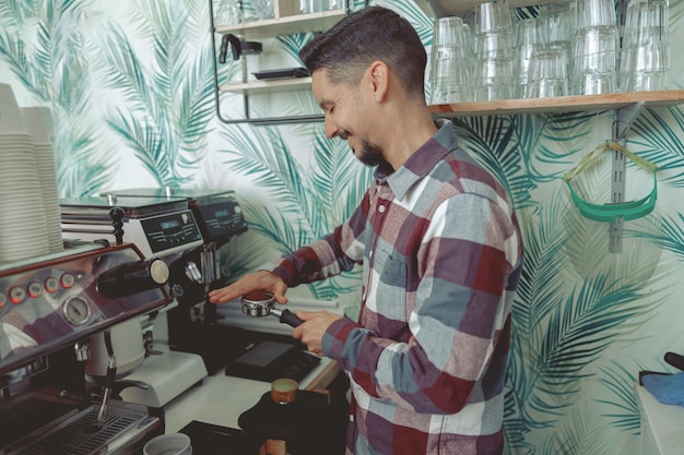 Retrato de sorridente barista preparando café no café