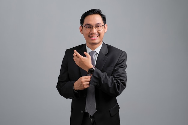 Retrato de sorridente jovem empresário bonito em terno formal, sentindo-se relaxado e confiante, olhando para a câmera isolada no fundo cinza