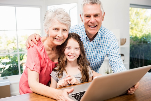 Retrato, de, sorrindo, avós, e, neta, usando computador portátil, casa