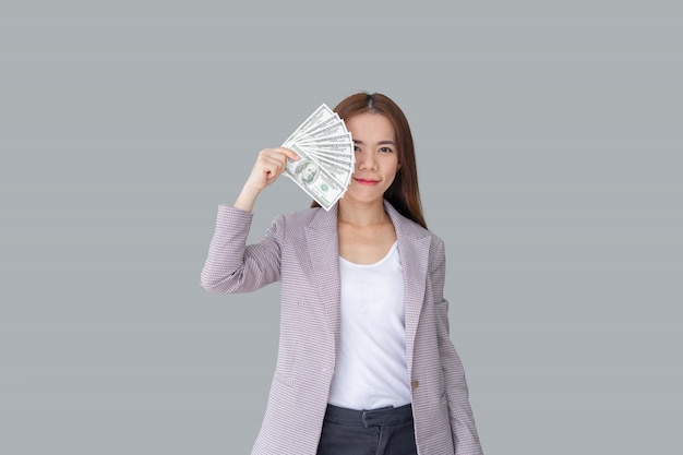 Retrato de sorrindo linda mulher asiática, escondendo o rosto por trás do monte de notas de dinheiro