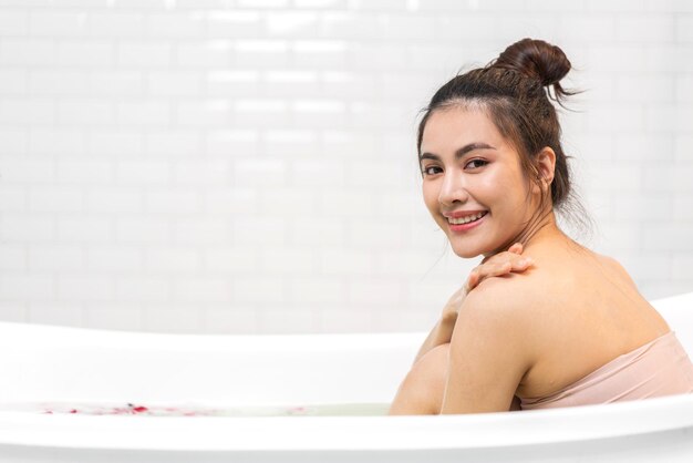 Retrato de sorrir de beleza feliz, mulher bonita asiática, tratamento de spa de pele branca fresca e saudável, desfrutar de relaxar tomando banho e tomar banho com spa de espuma de bolha na banheira no banheiro