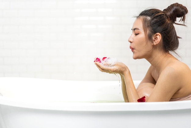 Retrato de sorrir de beleza feliz, mulher bonita asiática, tratamento de spa de pele branca fresca e saudável, desfrutar de relaxar tomando banho e tomar banho com spa de espuma de bolha na banheira no banheiro