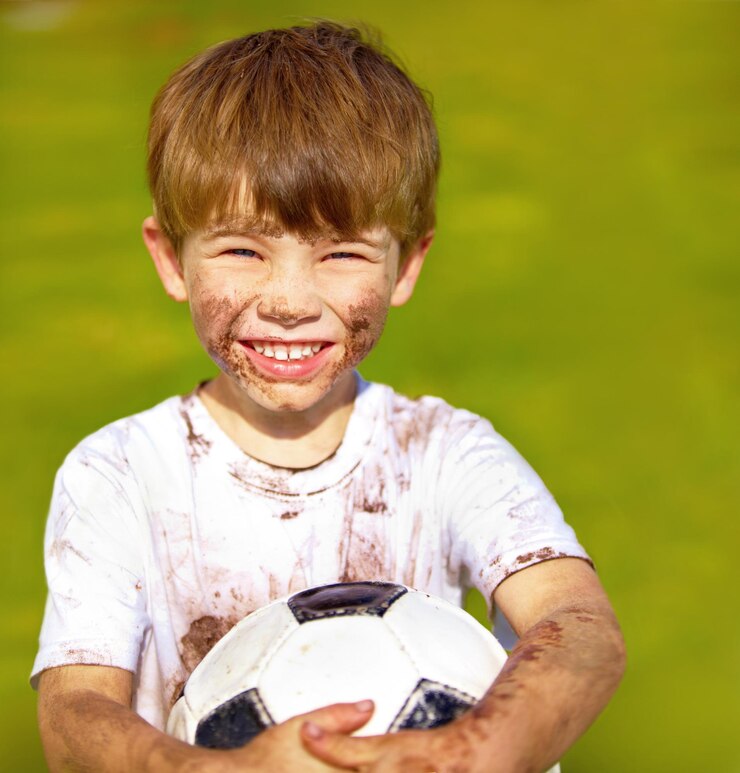 Foto retrato de sorriso e criança com bola de futebol ao ar livre para exercício esportivo ou jogo no jardim no verão cara de menino e menino feliz com bola de fútbol no parque com lama bagunçada ou suja para recreação na suécia
