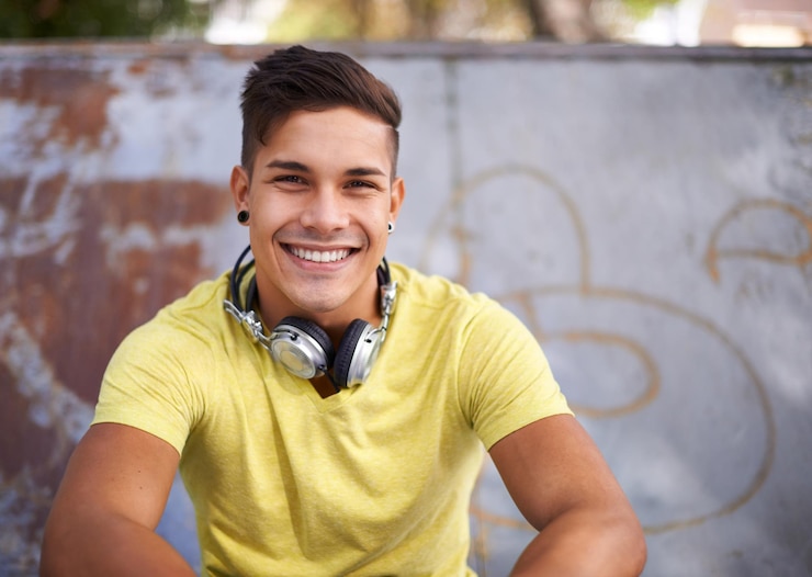 Foto retrato de sorriso e jovem no skatepark para prática de patinação ou treinamento para competição gente feliz e rosto de pessoa masculina legal sentada na rampa com atitude positiva, boa e confiante