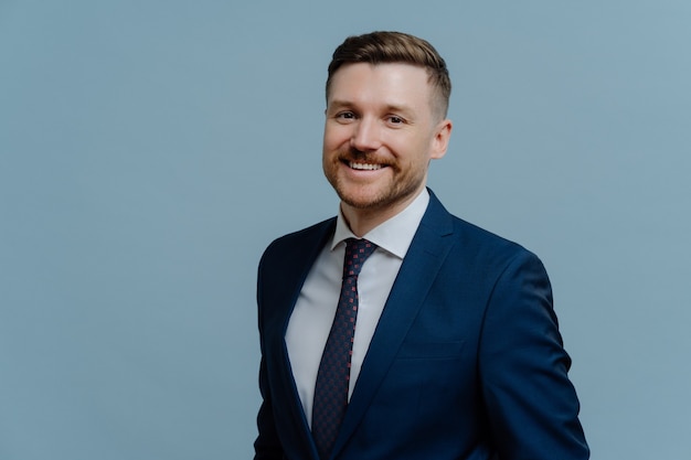 Retrato de tiro na cabeça de homem de negócios alegre feliz ou empresário masculino com roupa formal, olhando feliz e sorrindo para a câmera em pé isolado sobre fundo azul claro. Conceito de crescimento de carreira