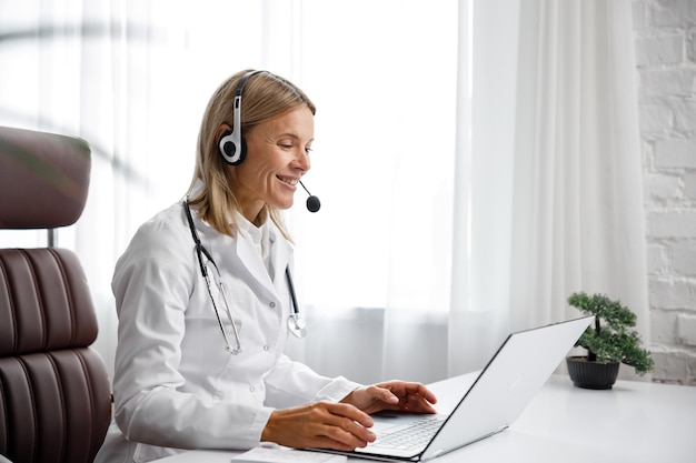 Retrato de tiro na cabeça de telemedicina de uma médica sorridente em fones de ouvido olhando para a câmera de uma médica feminina