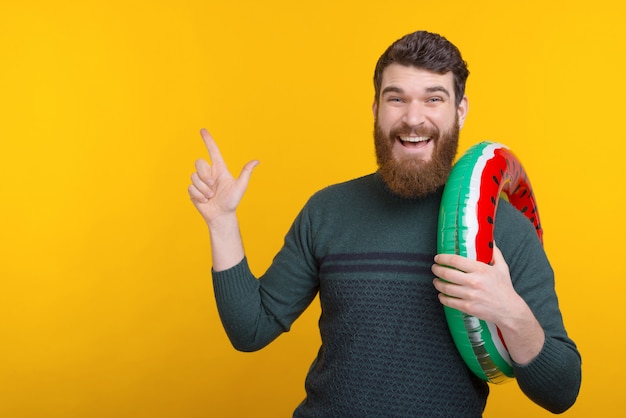 Retrato de trabalhador alegre segurando nadar círculo e apontando para fora