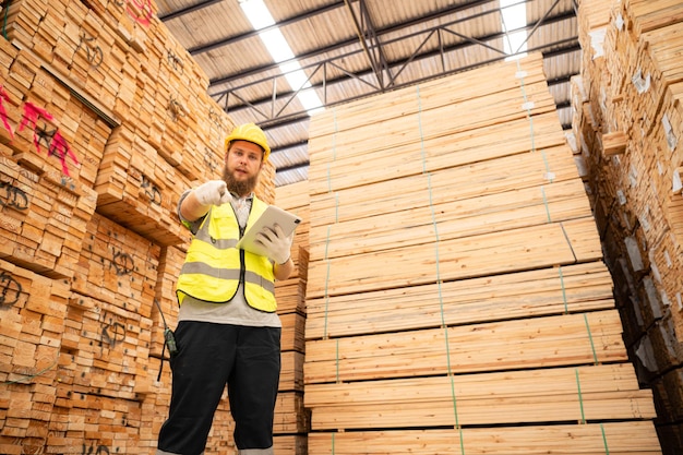Retrato de trabalhador de armazém verificando estoque de paletes de madeira em armazém