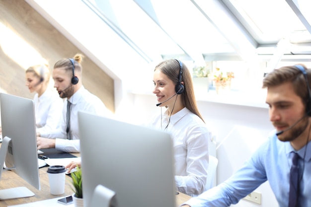 Retrato de trabalhador de call center acompanhado por sua equipe. Operador de suporte ao cliente sorridente no trabalho.