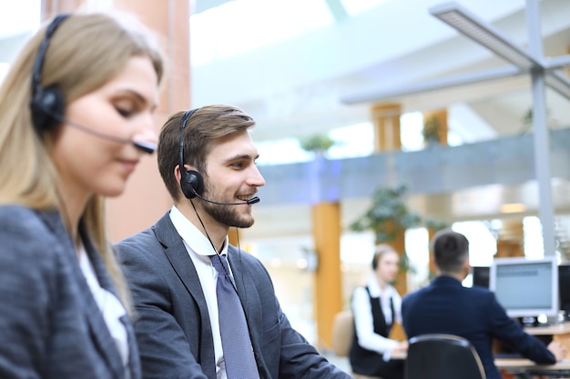 Retrato de trabalhador de call center acompanhado por sua equipe. Operador de suporte ao cliente sorridente no trabalho.