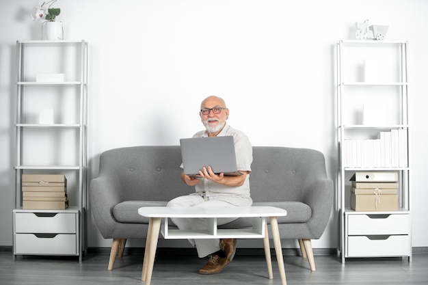 Retrato de trabalhador de escritório sênior com um laptop homem sênior com barba cinzenta tem um emprego em um laptop em