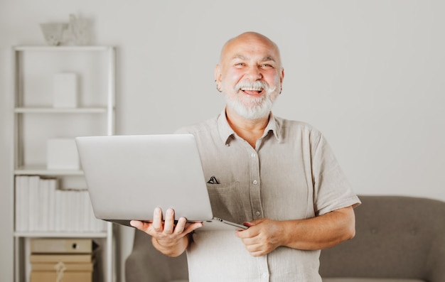 Retrato de trabalhador de escritório sênior feliz com um laptop sênior com barba grisalha tem um emprego em lapto