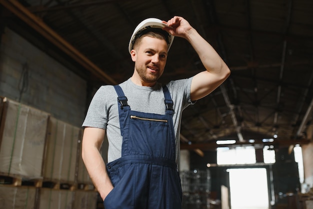 Retrato de trabalhador masculino feliz no armazém em pé entre as prateleiras