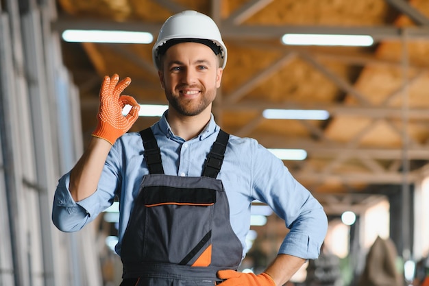 Retrato de trabalhador sorridente em pé pela máquina de produção industrial