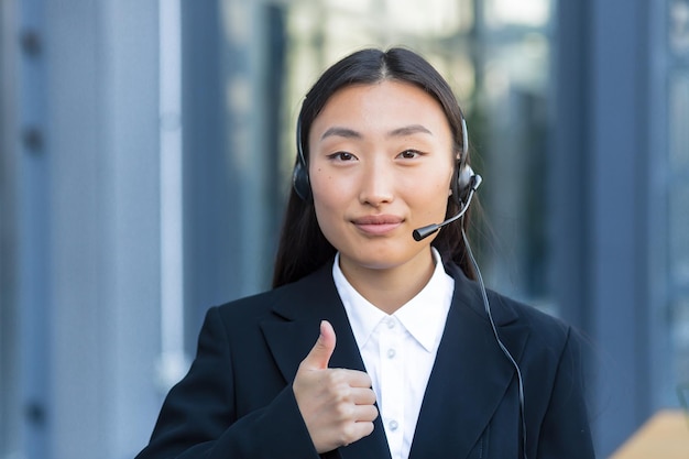 Retrato de trabalhadora de call center feminina, mulher asiática com fone de ouvido olhando para a câmera, foto de perto