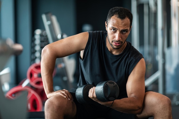 Retrato de treinamento de atleta masculino afro-americano com haltere no ginásio