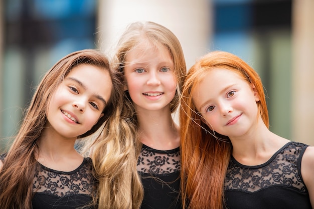 Retrato de três adolescentes com cabelos soltos, loira, ruiva e morena de verão na rua. Vloses se desenvolvem no vento.