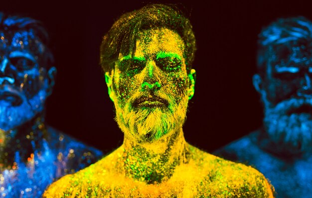 Retrato de três homens barbudos pintados em pó fluorescente.