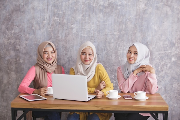 Retrato de três irmãos usando hijab tendo projeto juntos