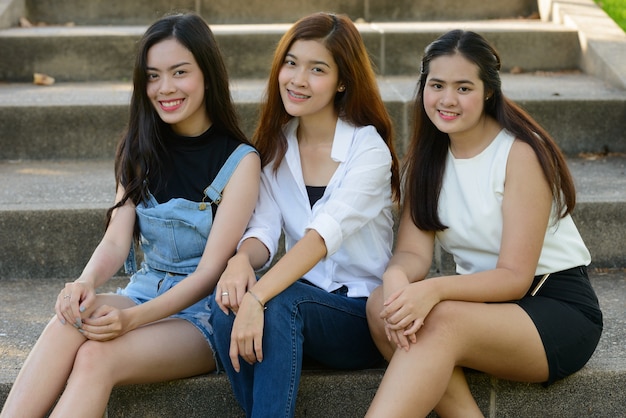 Retrato de três jovens mulheres asiáticas como amigas relaxando no parque ao ar livre