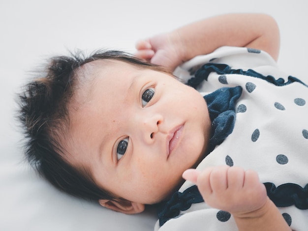 Retrato de três semanas de bebê recém-nascido asiático australiano ou bebê deitado na cama branca e abrindo os olhosxA