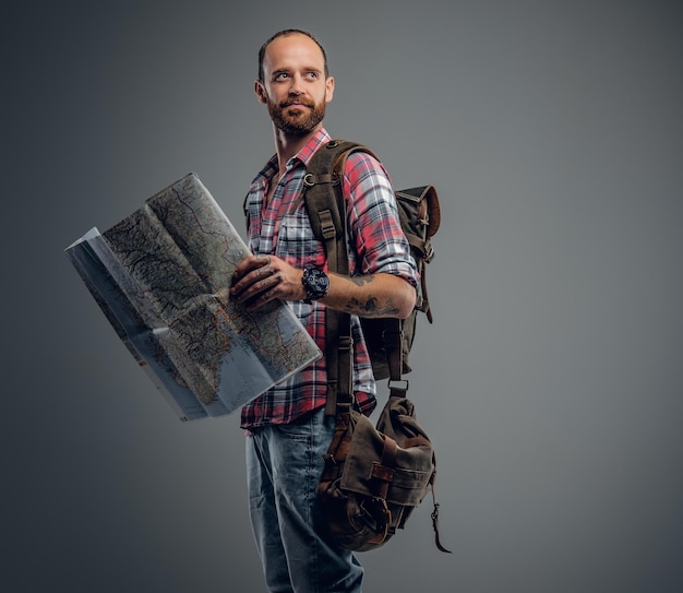 Retrato de turista masculino segurando o mapa da cidade isolado no fundo cinza.