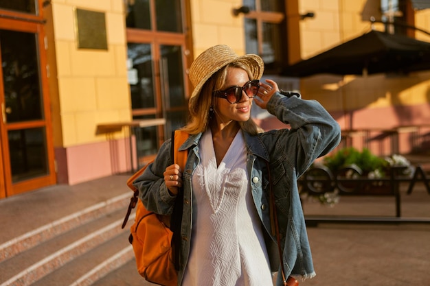 Retrato de turista milenar de chapéu e óculos de sol com mochila na cidade.