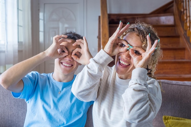 Retrato de um adolescente adulto feliz posando com a mãe se divertindo em casa juntos, a jovem mãe faz gestos engraçados com o filho adulto xa