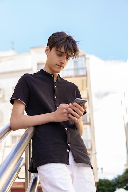 Retrato de um adolescente caucasiano usando um smartphone na cidade