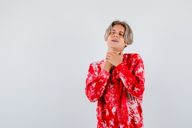 Foto retrato de um adolescente loiro fazendo um gesto de suicídio com uma camisa grande e uma vista frontal sem esperança