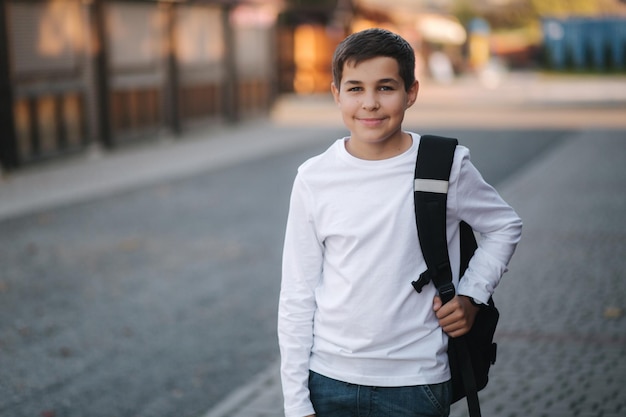 Retrato de um adolescente sorridente feliz em moletom branco com mochila do lado de fora