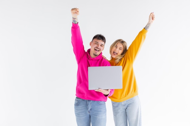 Retrato de um adorável homem e mulher segurando laptop prateado enquanto estava isolado sobre fundo branco