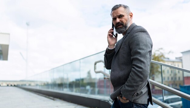 Retrato de um advogado adulto maduro com cabelos grisalhos e barba falando ao telefone na varanda de