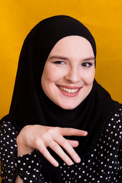 Retrato, de, um, alegre, islamic, mulher olha, câmera, contra, fundo amarelo