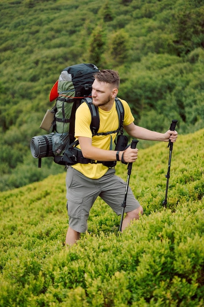 Retrato de um alpinista com bastões de trekking e mochila subindo ou descendo trilhas de montanha