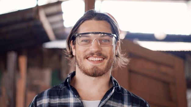 Retrato de um artesão feliz olhando um sorriso para a câmera na oficina de carpintaria