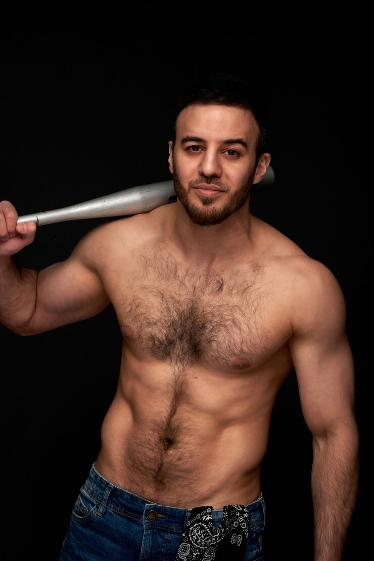 Foto retrato de um atleta do sexo masculino com um torso nu com um taco de beisebol nas mãos em um fundo escuro