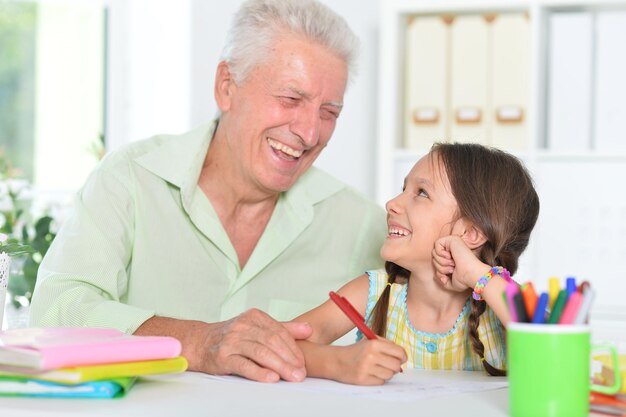 Retrato de um avô feliz com a neta desenhando juntos