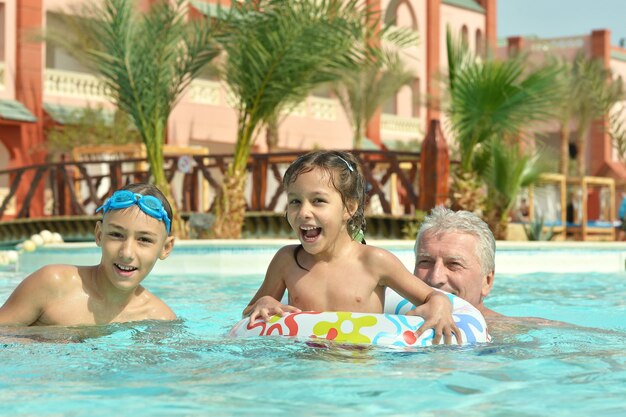 Retrato de um avô feliz com netos na piscina