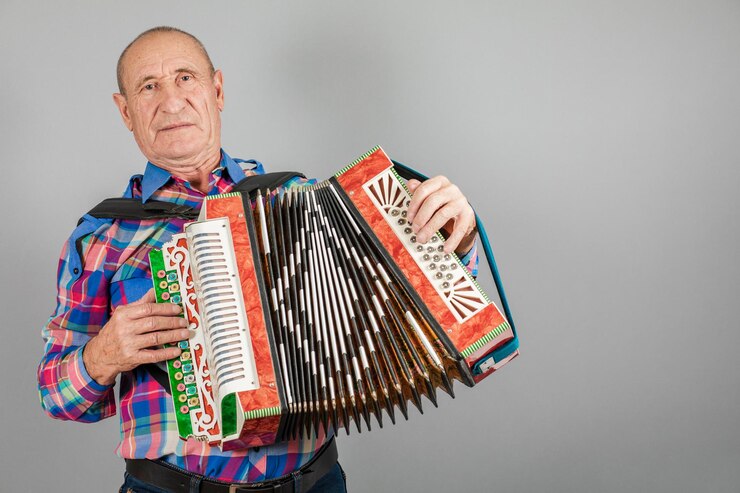 Foto retrato de um avô homem toca acordeão em um fundo cinza