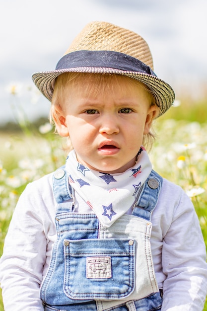 Retrato de um bebê adorável com flores no campo de camomila