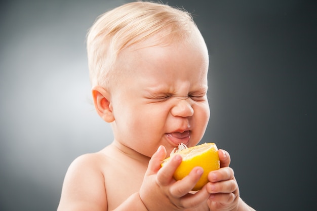 Retrato de um bebê engraçado apertando os olhos de limão azedo